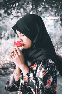 Midsection of woman holding hat against plants