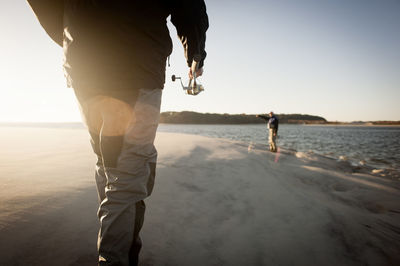 Men preparing for fishing at beach during sunset