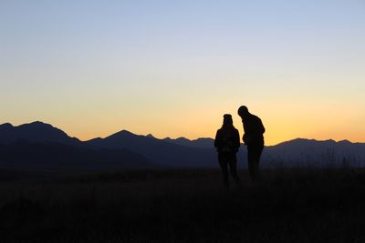 Silhouette people standing on field against clear sky