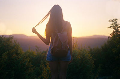 Rear view of woman standing on landscape against sky