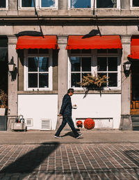 Side view of man walking on street against building
