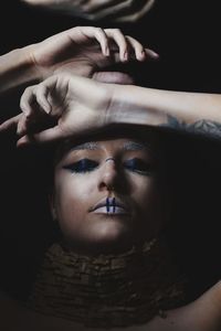 Close-up portrait of young woman over black background