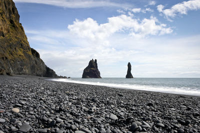 Scenic view of beach against cloudy sky