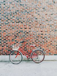 Bicycle parked against brick wall