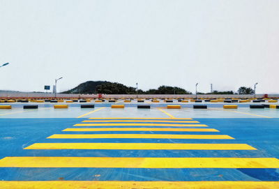 Zebra crossing on road against clear sky