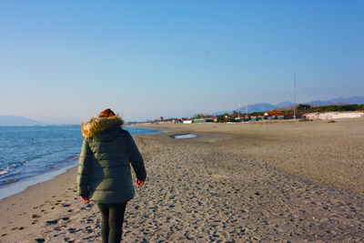 Indistinct figure of lonely woman at the sea on the beach in winter at sunset in tuscany dune