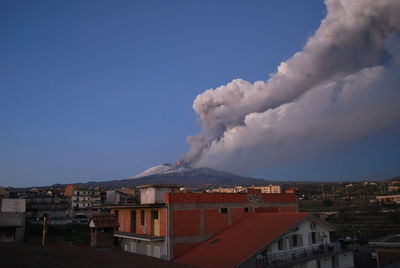 Smoke emitting from volcanic mountain against blue sky