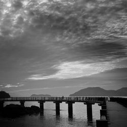 Pier on sea against cloudy sky