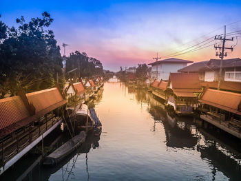 Boats moored in canal against sky during sunset