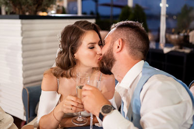 Bridegroom kissing while holding champagne flute during wedding ceremony