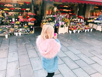 Rear view of woman standing with flowers in market