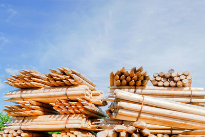 Stack of firewood for sale at market stall against sky
