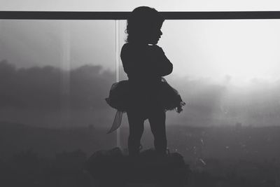 Rear view of silhouette boy against sky