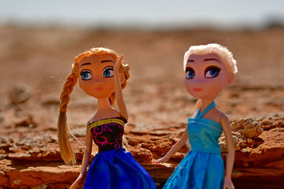 Blonde dolls posed in the rocky desert on location in blue silk and satin dresses