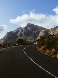 Road by mountains against sky