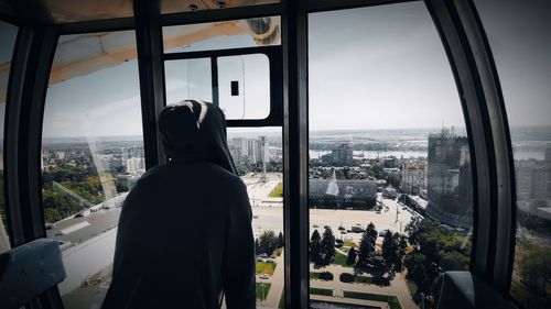 Rear view of man looking through window