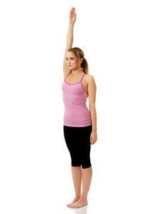 Confident young woman with hand raised exercising against white background