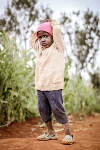 Full length of boy standing by tree