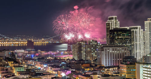 Firework display over illuminated buildings in city at night