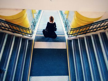 High angle view of woman with luggage moving down on steps in building