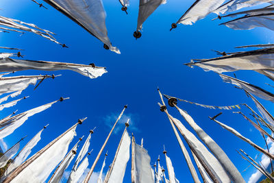 Low angle view of cranes hanging against blue sky