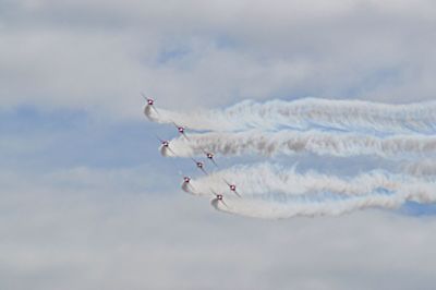 Low angle view of airshow against cloudy sky