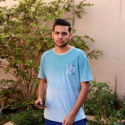 Portrait of young man standing against plants