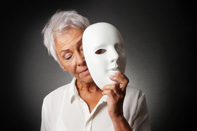 Senior woman wearing mask against black background
