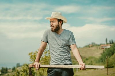 Man looking away while standing against sky