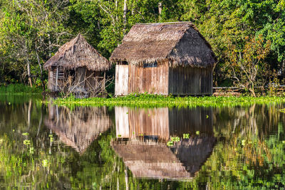 Shacks and trees with reflection on water in lake