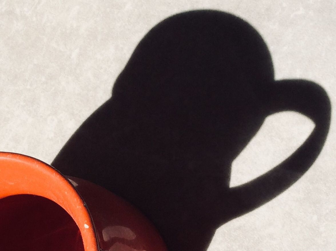 shadow, sunlight, close-up, day, one person, real people, focus on shadow, nature, high angle view, indoors, cup, drink, wall - building feature, holding, food and drink, refreshment