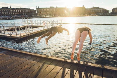 People at swimming pool by lake against sky