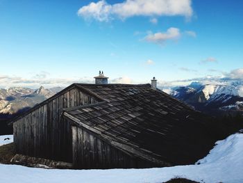 Old house on mountain during winter against sky