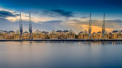 River amidst buildings against sky during sunset