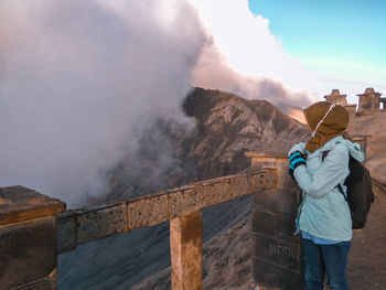 Rear view of people standing on mountain against sky