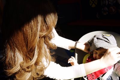 Mother dressing up child at home on sunny day