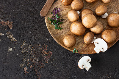 Fresh champignon on a wooden plate, dark brown texture background. brown mushrooms.