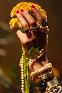 Cropped hand of woman with jewelry holding flower