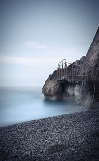 View of staircase on cliffs at coast against sky