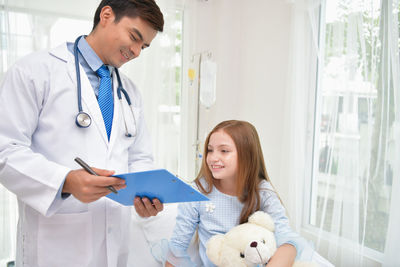 Doctor showing clipboard to girl in hospital