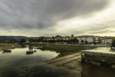 Scenic view of river by city against sky