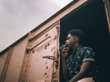 Side view of young man looking away against sky