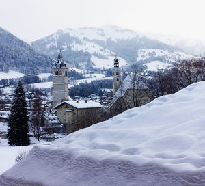 Snow covered houses and mountains against sky