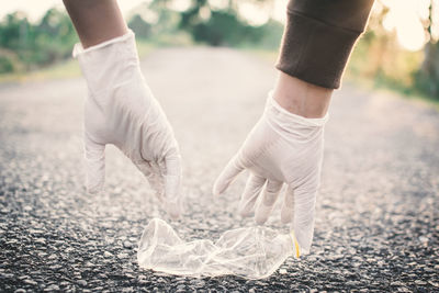 Close-up of hands collecting waste on road