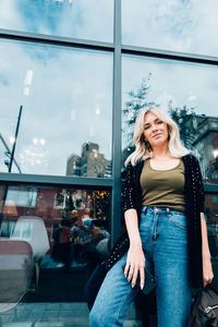 Portrait of smiling young woman in glass window