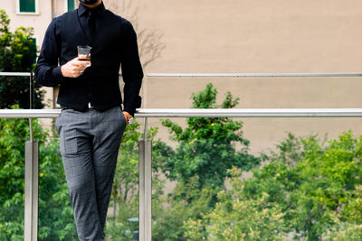 Man standing by railing against trees