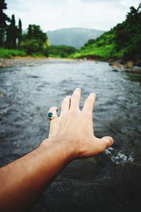 Close-up of hand gesturing over river