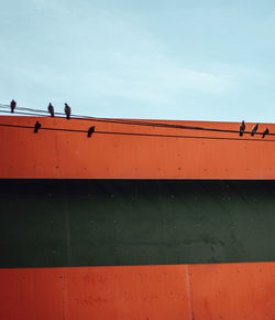 Low angle view of people on wall against sky