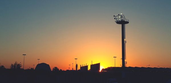 Silhouette street light and buildings against sky during sunset