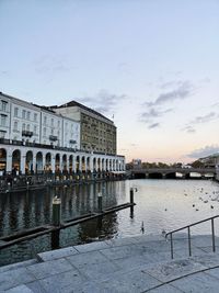 Buildings at waterfront against cloudy sky